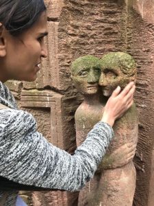 A young men is tutching a ssculpture representing a face on a wall