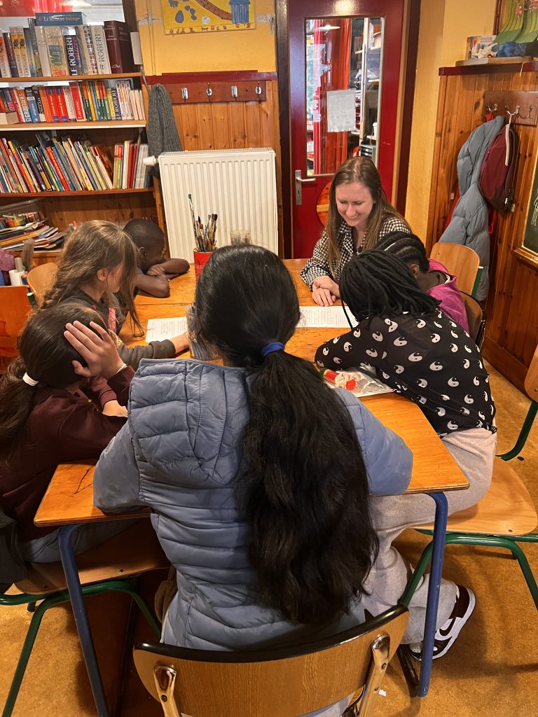 Kinga is sitting with children completing their homework