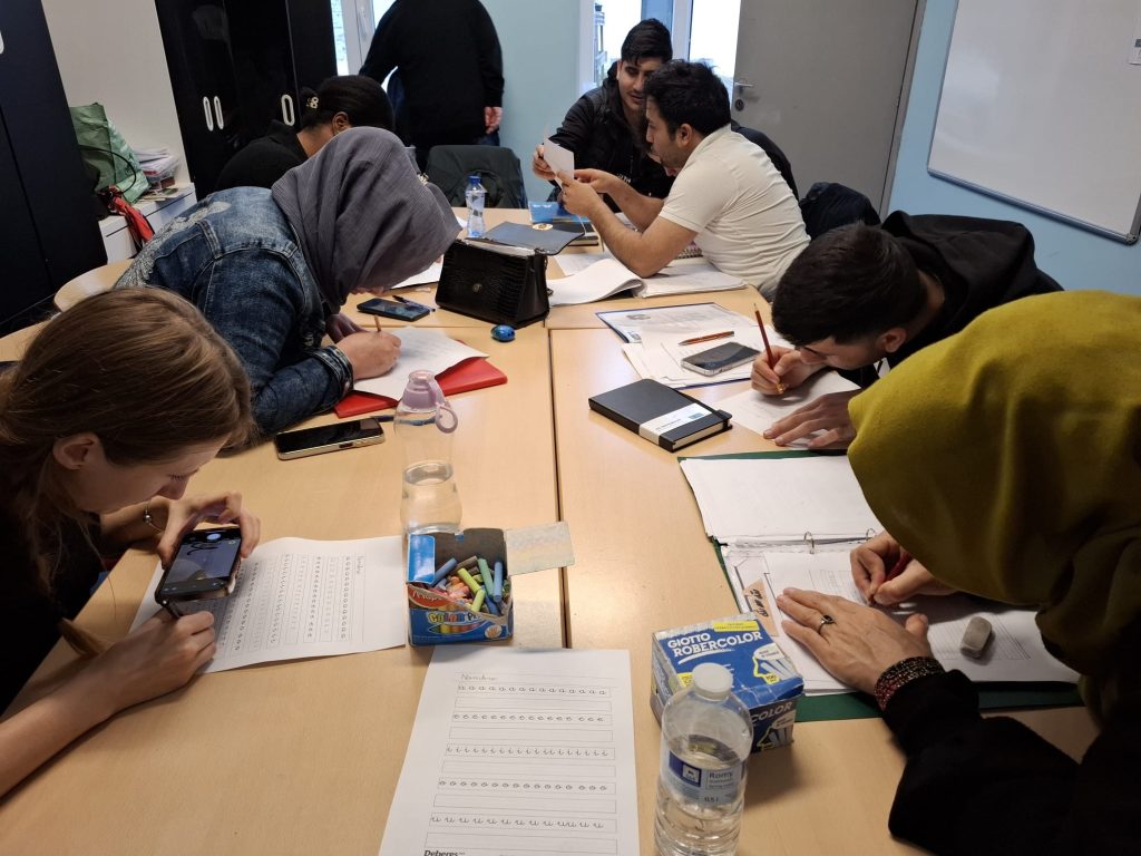 Adult students and Kinga compiling a document around a table