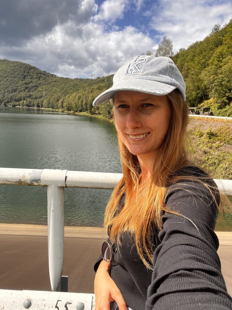 Kinga smiling for a selfie in front of a lake.