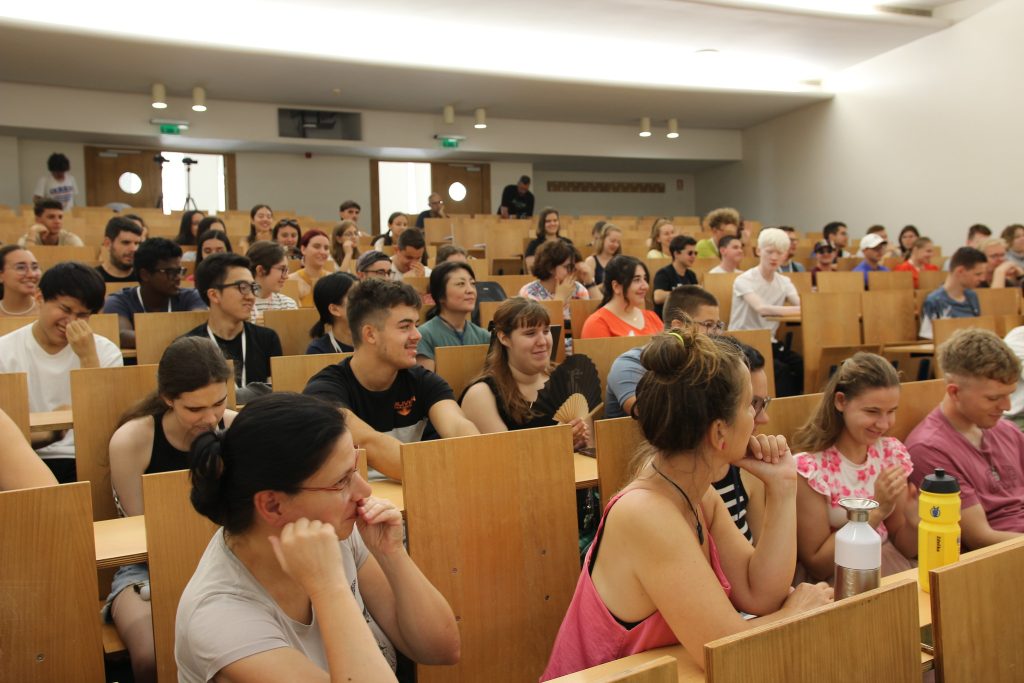 Participants sitting during a lecture. Many of them are smiling.